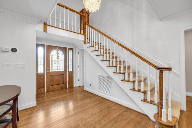foyer featuring stairway, wood finished floors, visible vents, and ornamental molding