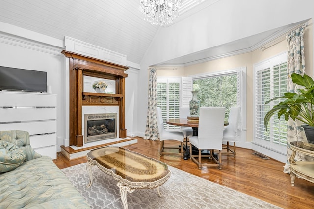 living area featuring an inviting chandelier, wood finished floors, visible vents, a high end fireplace, and lofted ceiling