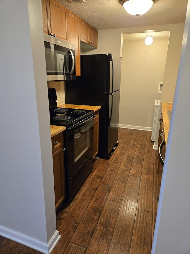 kitchen featuring stainless steel microwave, dark wood-style flooring, light countertops, black range with electric stovetop, and baseboards