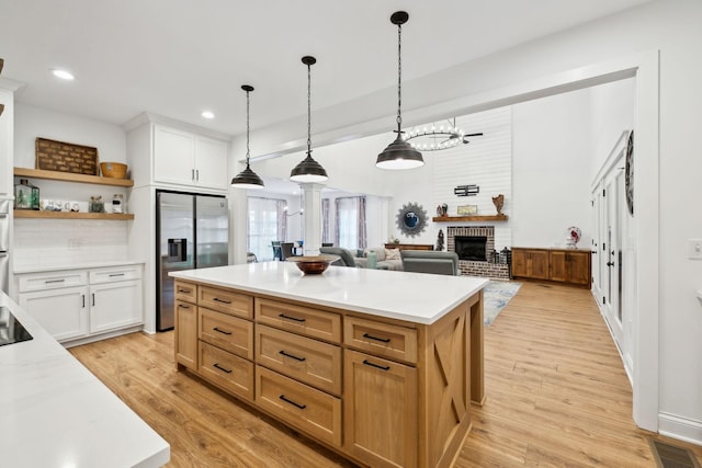 kitchen featuring a fireplace, light countertops, stainless steel fridge, and decorative columns