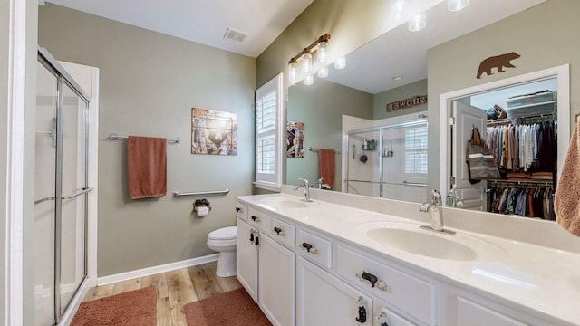 bathroom featuring a sink, a shower stall, wood finished floors, and visible vents