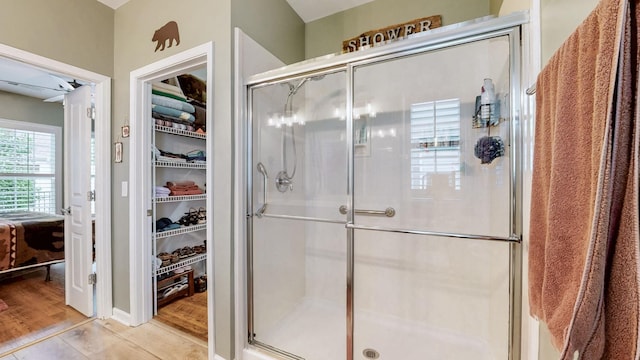 bathroom with wood finished floors, a shower stall, and a walk in closet