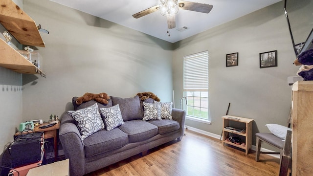 living area featuring baseboards, visible vents, wood finished floors, and a ceiling fan