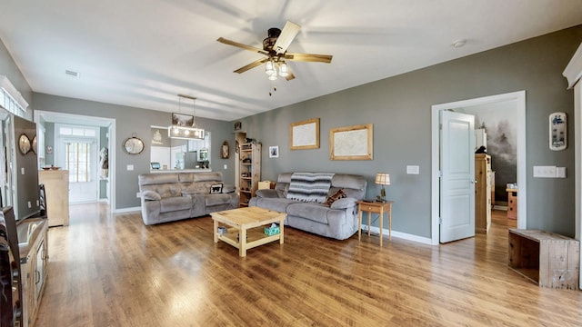living room featuring wood finished floors, a ceiling fan, and baseboards