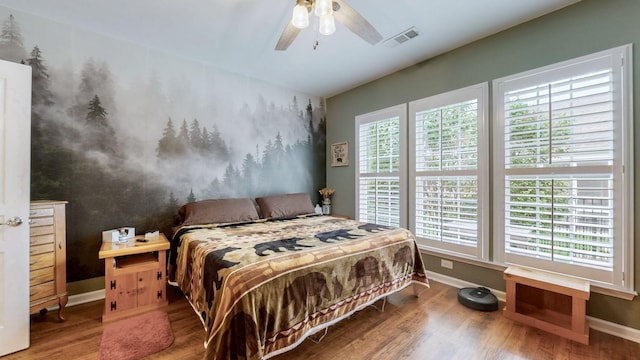 bedroom featuring baseboards, visible vents, wood finished floors, and multiple windows