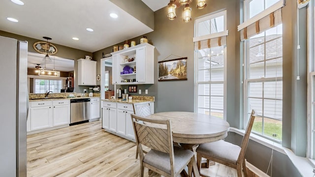 kitchen with open shelves, white cabinets, appliances with stainless steel finishes, and light wood-style floors