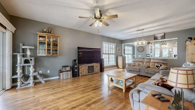 living area featuring baseboards, wood finished floors, and ceiling fan