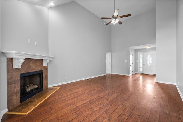 unfurnished living room with high vaulted ceiling, ceiling fan, wood finished floors, and a fireplace