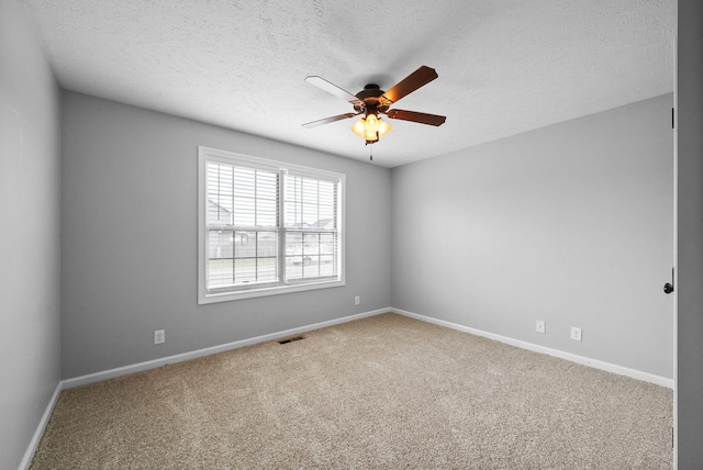 carpeted spare room featuring baseboards, visible vents, ceiling fan, and a textured ceiling