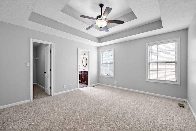 unfurnished bedroom featuring a raised ceiling, visible vents, and carpet