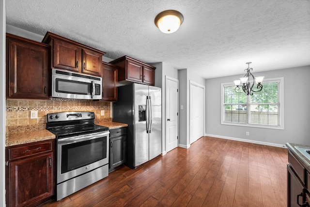 kitchen featuring a chandelier, dark wood-type flooring, backsplash, baseboards, and appliances with stainless steel finishes