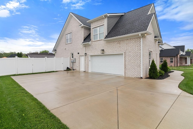 view of side of home with a garage, brick siding, driveway, roof with shingles, and fence
