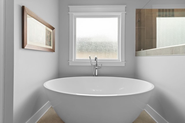 bathroom featuring tiled shower, a soaking tub, and baseboards