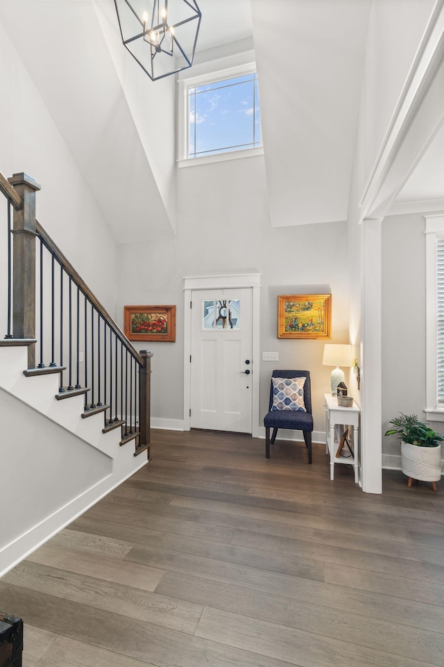 foyer featuring stairway, wood finished floors, a notable chandelier, and a towering ceiling