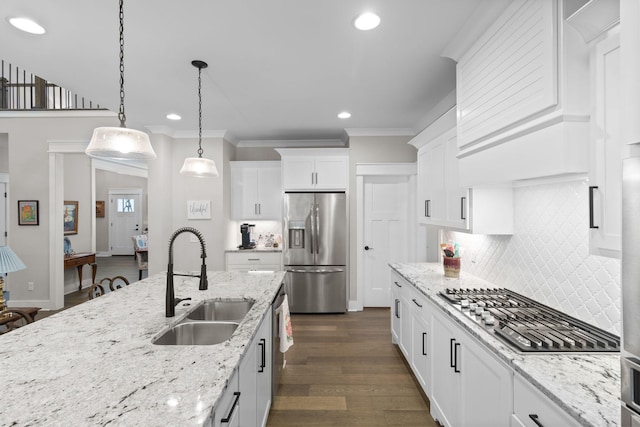 kitchen with appliances with stainless steel finishes, backsplash, crown molding, and a sink
