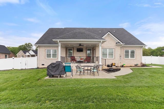 back of property featuring a fenced backyard, a yard, brick siding, a patio area, and a ceiling fan
