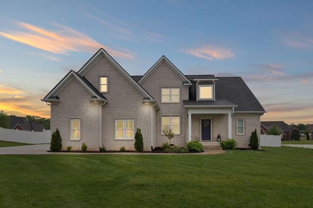 traditional home featuring fence, brick siding, and a front lawn