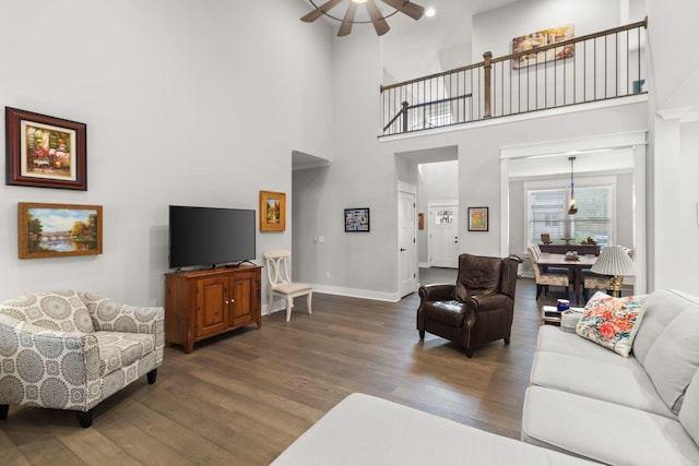 living area featuring a high ceiling, a ceiling fan, wood finished floors, and baseboards