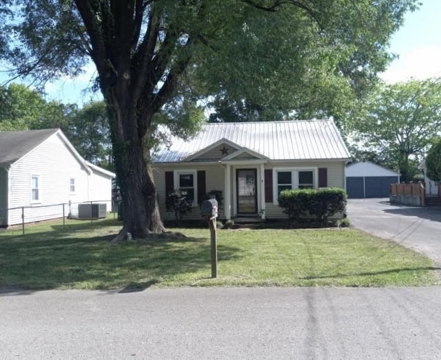 view of front facade featuring fence, metal roof, a garage, central AC unit, and a front lawn