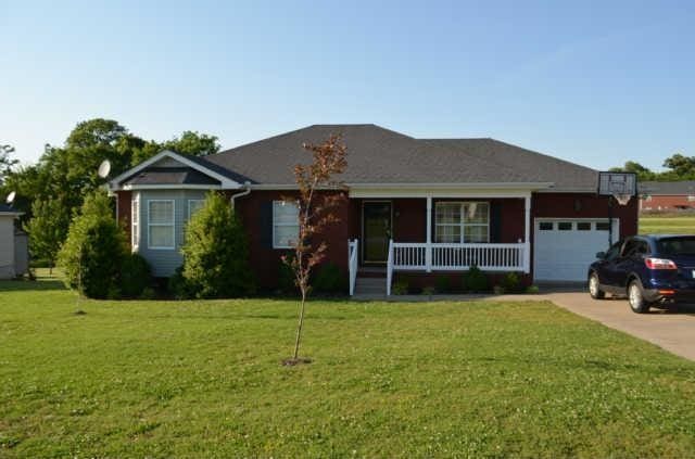 ranch-style home with covered porch, a garage, a front yard, and concrete driveway