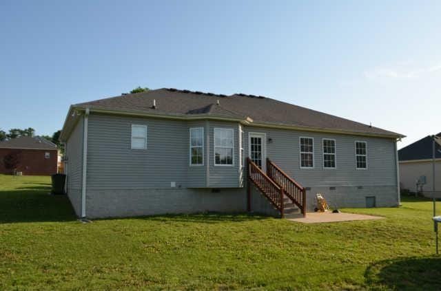 rear view of house featuring a lawn, a patio, and crawl space
