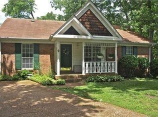 craftsman-style home with a front yard, covered porch, and brick siding