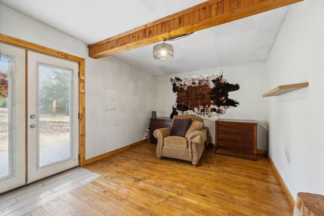 sitting room featuring beam ceiling, light wood finished floors, and baseboards