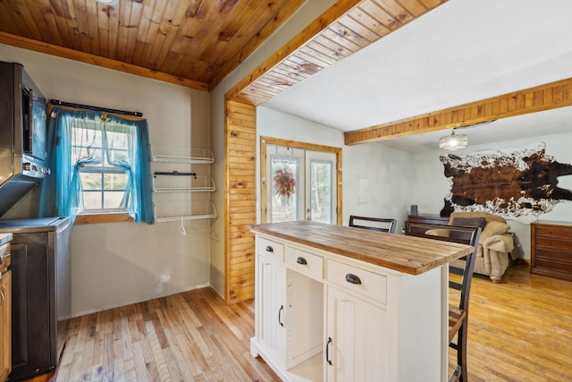 kitchen with wooden ceiling, wooden counters, a kitchen bar, white cabinetry, and light wood-type flooring