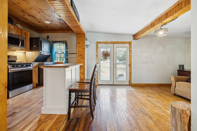 kitchen featuring light wood finished floors, baseboards, appliances with stainless steel finishes, and a healthy amount of sunlight