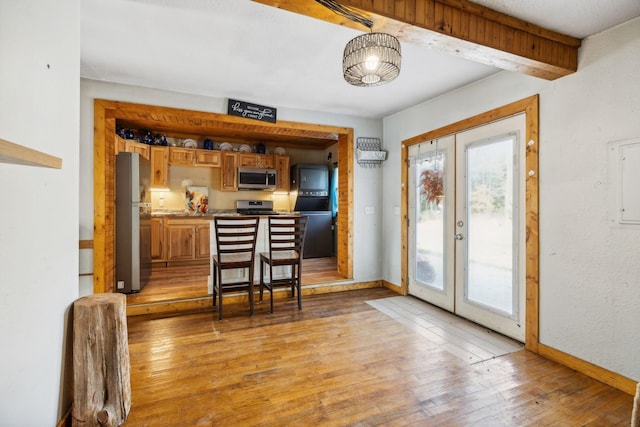 entryway featuring baseboards, french doors, light wood finished floors, and plenty of natural light