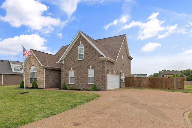 traditional-style home featuring concrete driveway, an attached garage, fence, brick siding, and a front lawn