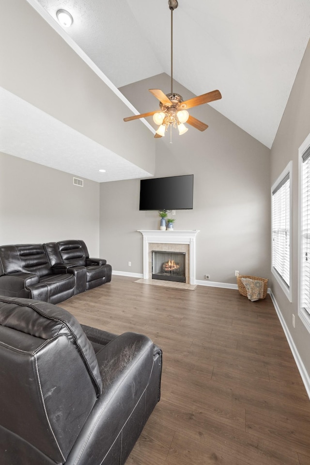 living room with visible vents, a tile fireplace, dark wood finished floors, a ceiling fan, and high vaulted ceiling