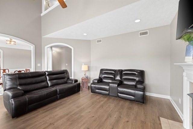living area featuring light wood finished floors, arched walkways, visible vents, and baseboards