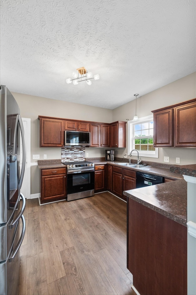 kitchen with dark countertops, a sink, dark wood-style flooring, and stainless steel appliances