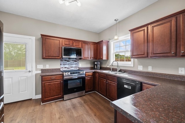 kitchen featuring appliances with stainless steel finishes, dark countertops, dark wood-style floors, and a sink