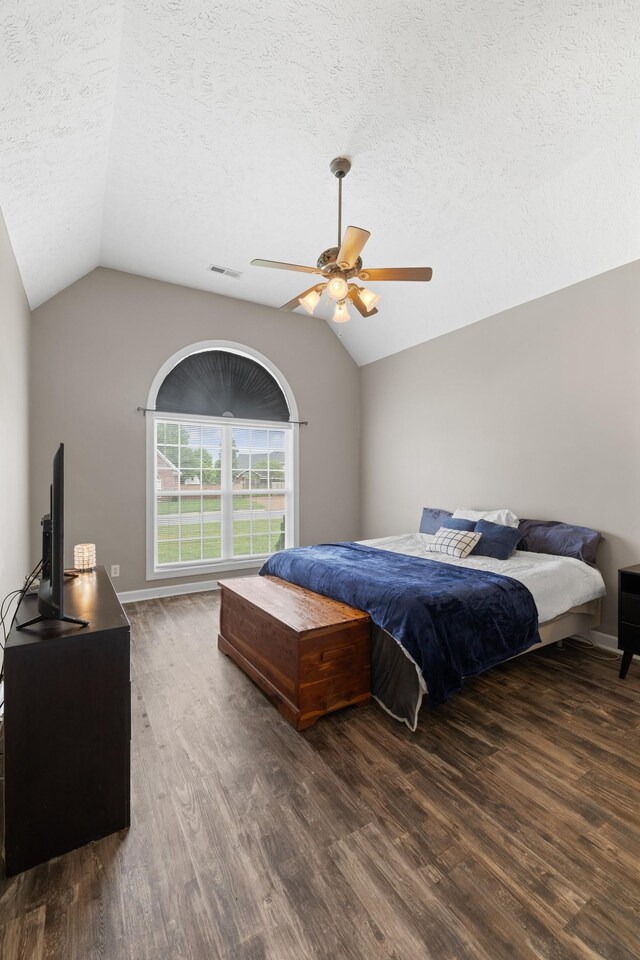 bedroom featuring a textured ceiling, visible vents, wood finished floors, and lofted ceiling