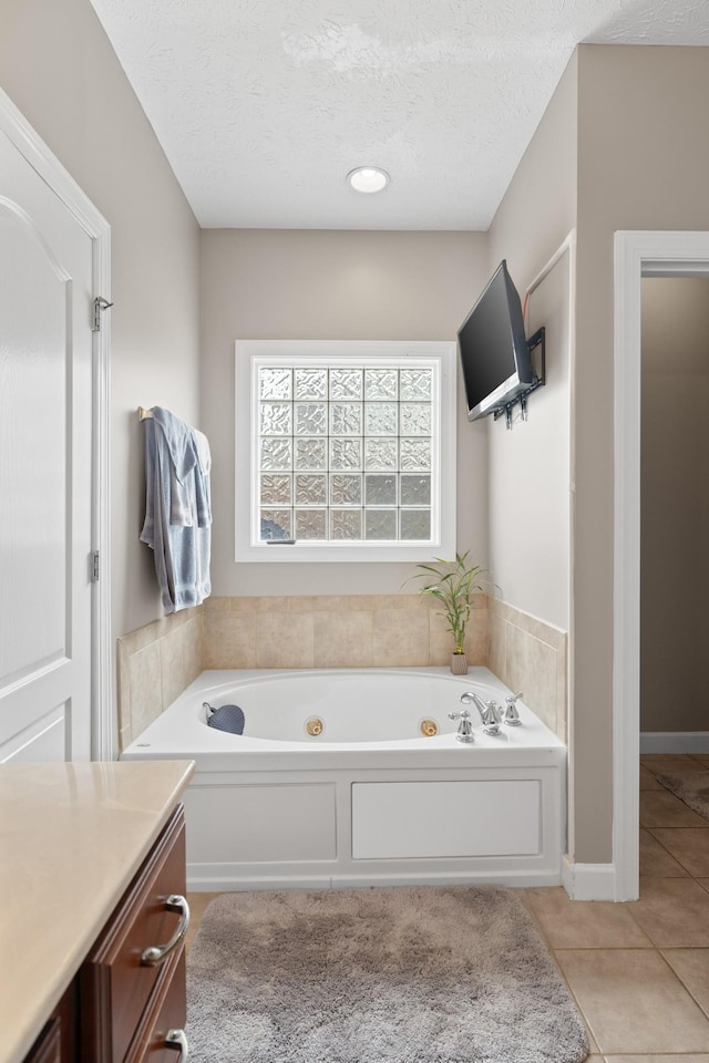 bathroom featuring tile patterned floors, a tub with jets, a textured ceiling, and vanity