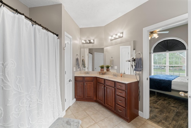 ensuite bathroom featuring ceiling fan, tile patterned flooring, double vanity, and a sink