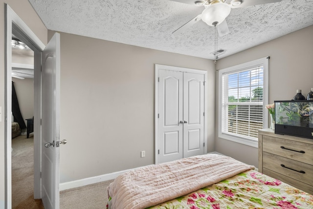 carpeted bedroom with a closet, ceiling fan, baseboards, visible vents, and a textured ceiling