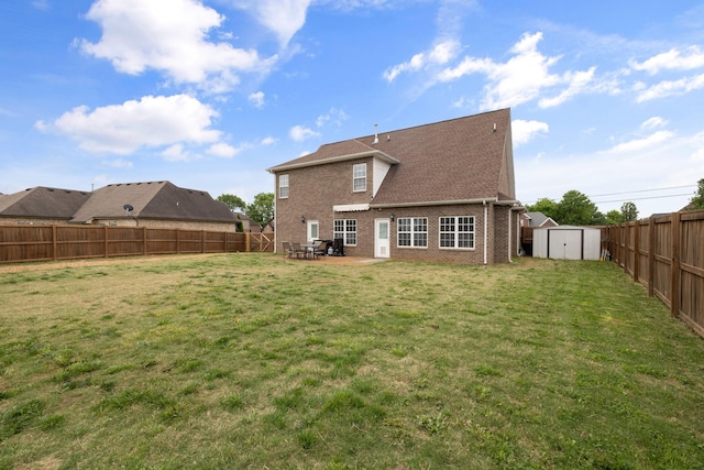 rear view of house featuring a fenced backyard, a storage unit, brick siding, an outbuilding, and a patio area