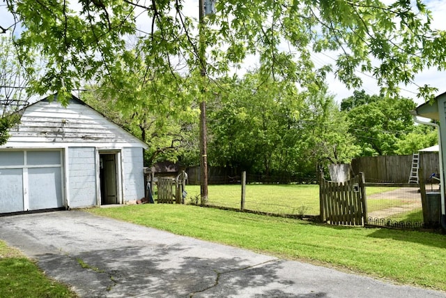 view of yard with an outdoor structure, driveway, fence private yard, and a gate