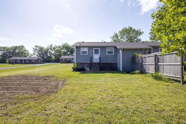 rear view of house featuring a lawn and fence
