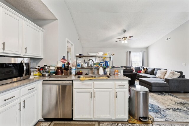 kitchen with appliances with stainless steel finishes, a sink, open floor plan, a ceiling fan, and a peninsula