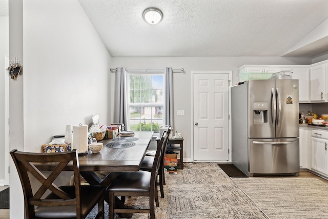 dining space with a textured ceiling and vaulted ceiling