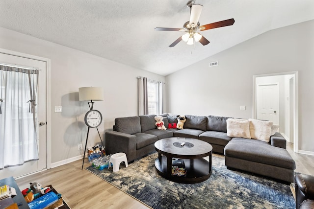 living area featuring vaulted ceiling, wood finished floors, a ceiling fan, and baseboards