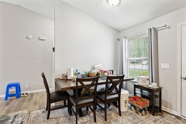 dining space featuring wood finished floors, a textured ceiling, and baseboards