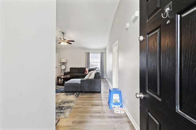 foyer entrance with light wood-style flooring, ceiling fan, and baseboards