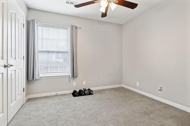carpeted spare room featuring a ceiling fan and baseboards