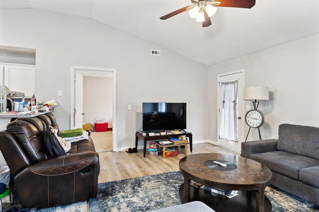 living area with light wood finished floors, lofted ceiling, ceiling fan, and baseboards