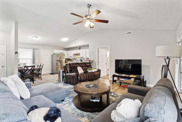 living room featuring ceiling fan, vaulted ceiling, light wood-style floors, and baseboards